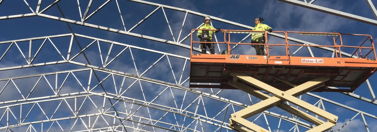 Operarios trabajando desde una plataforma tipo tijera en el montaje de una estructura metálica